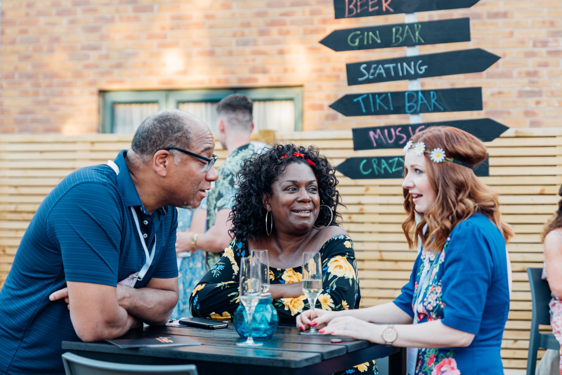 three adults chatting at outdoor bar table