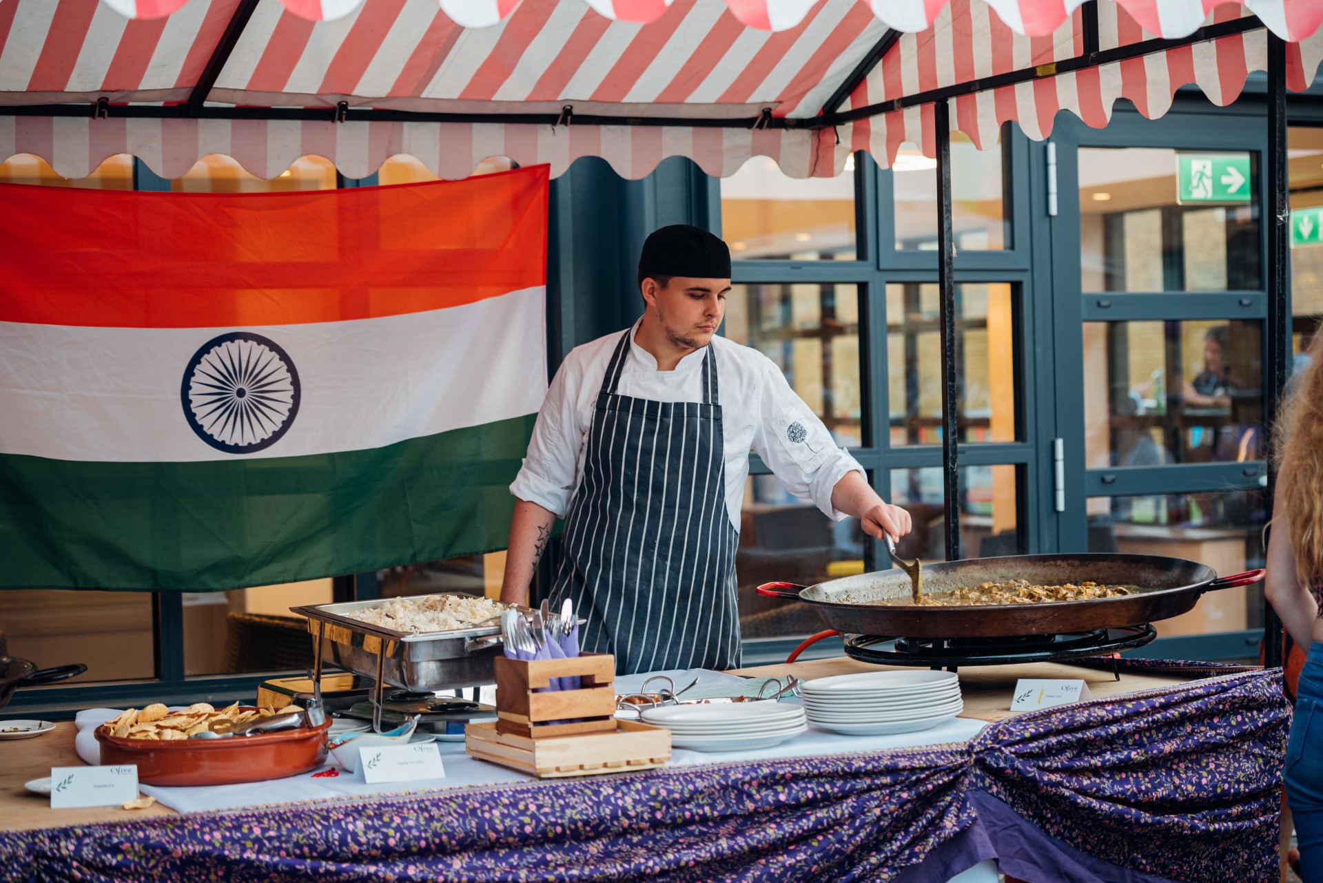 man cooking indian food in outdoor market stall
