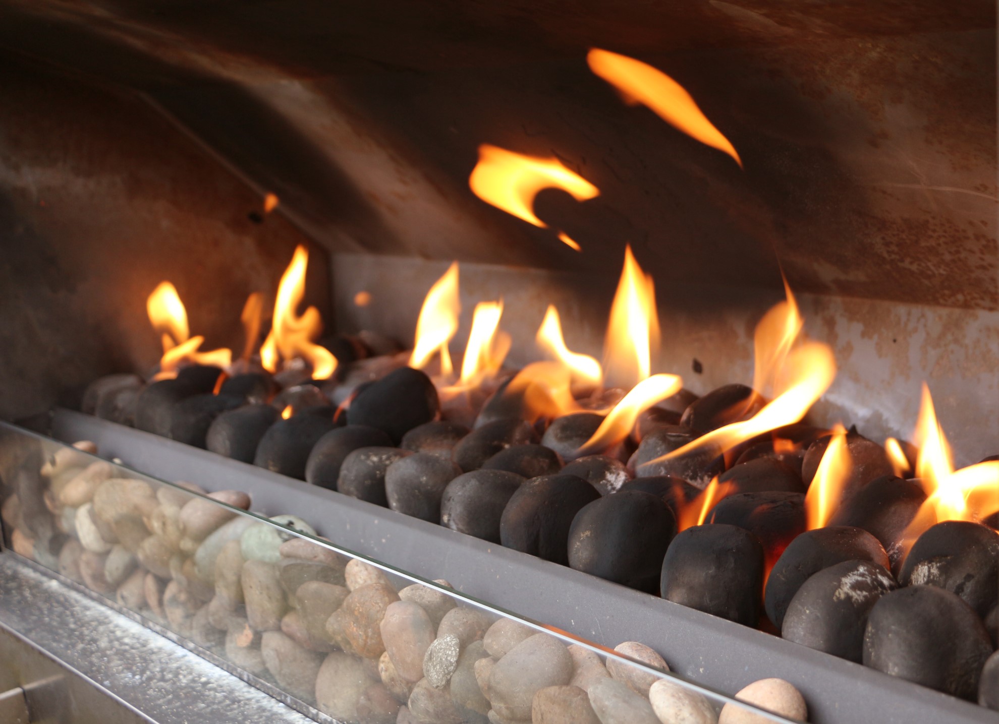 gas fireplace with black stones and flames