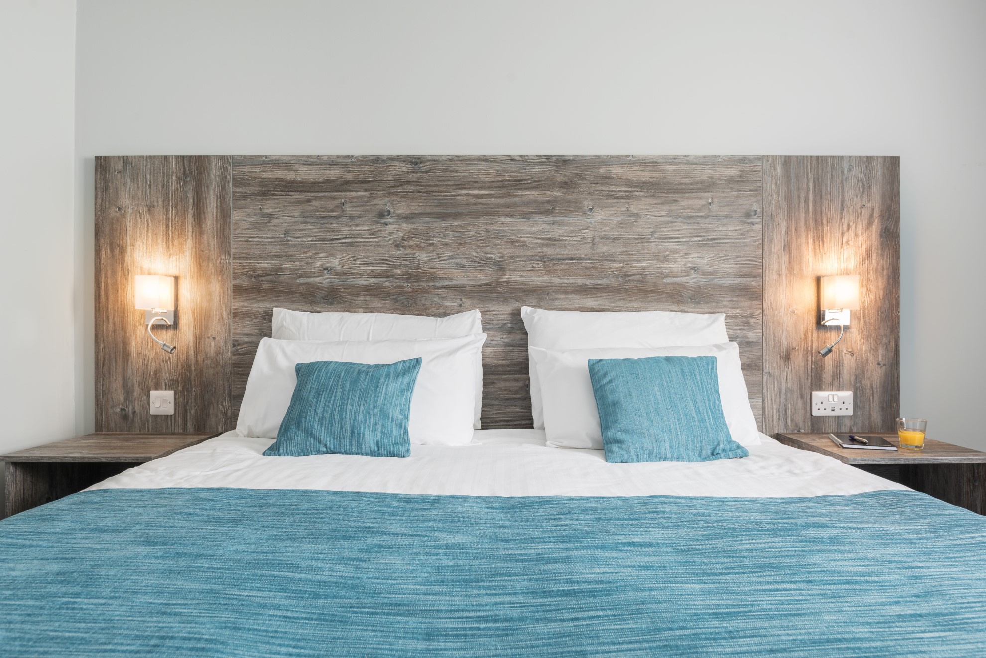 double bed with blue cushions and wooden headboard