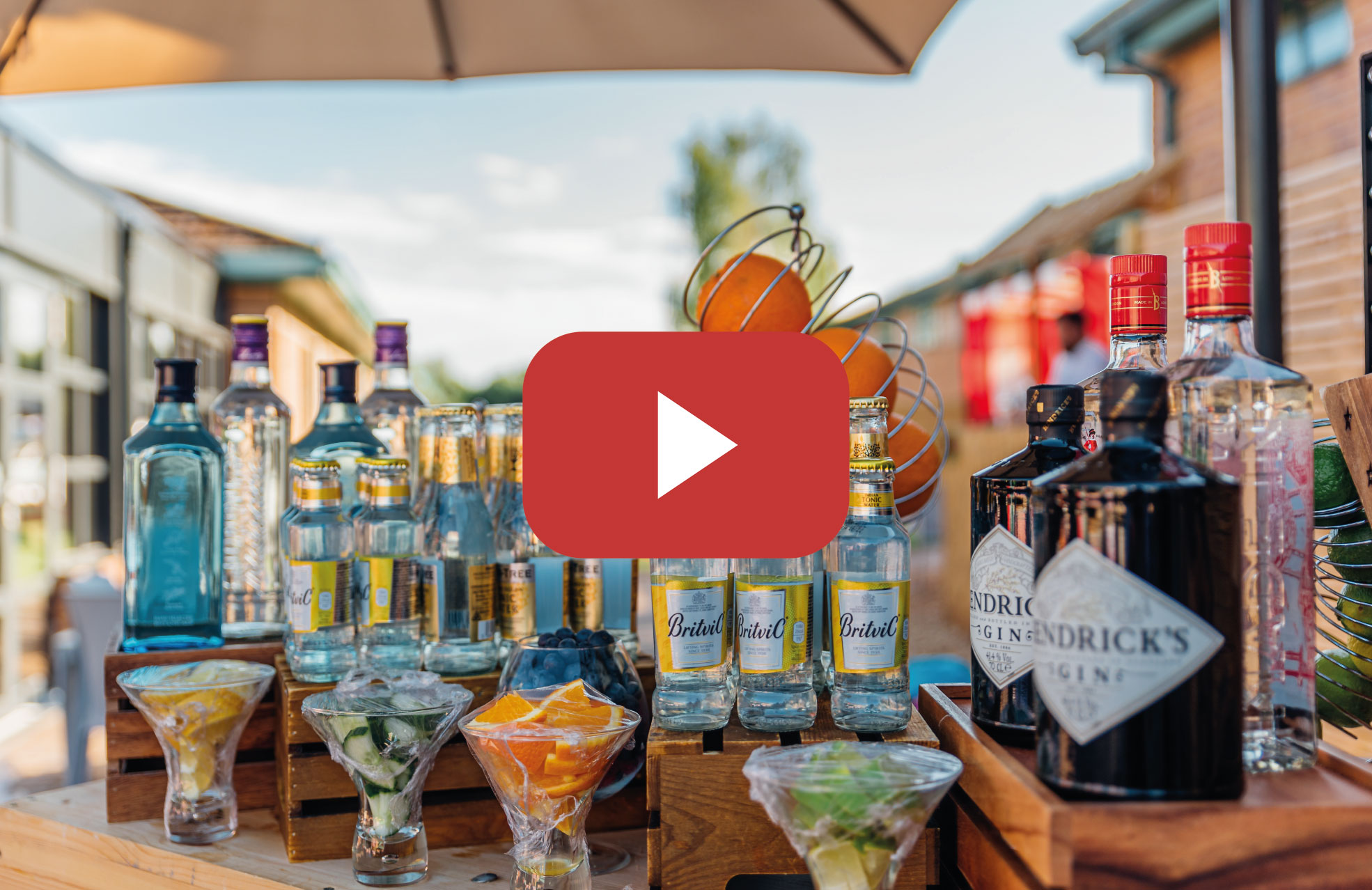 bottles of gin mixers and fruit slices on outdoor bar