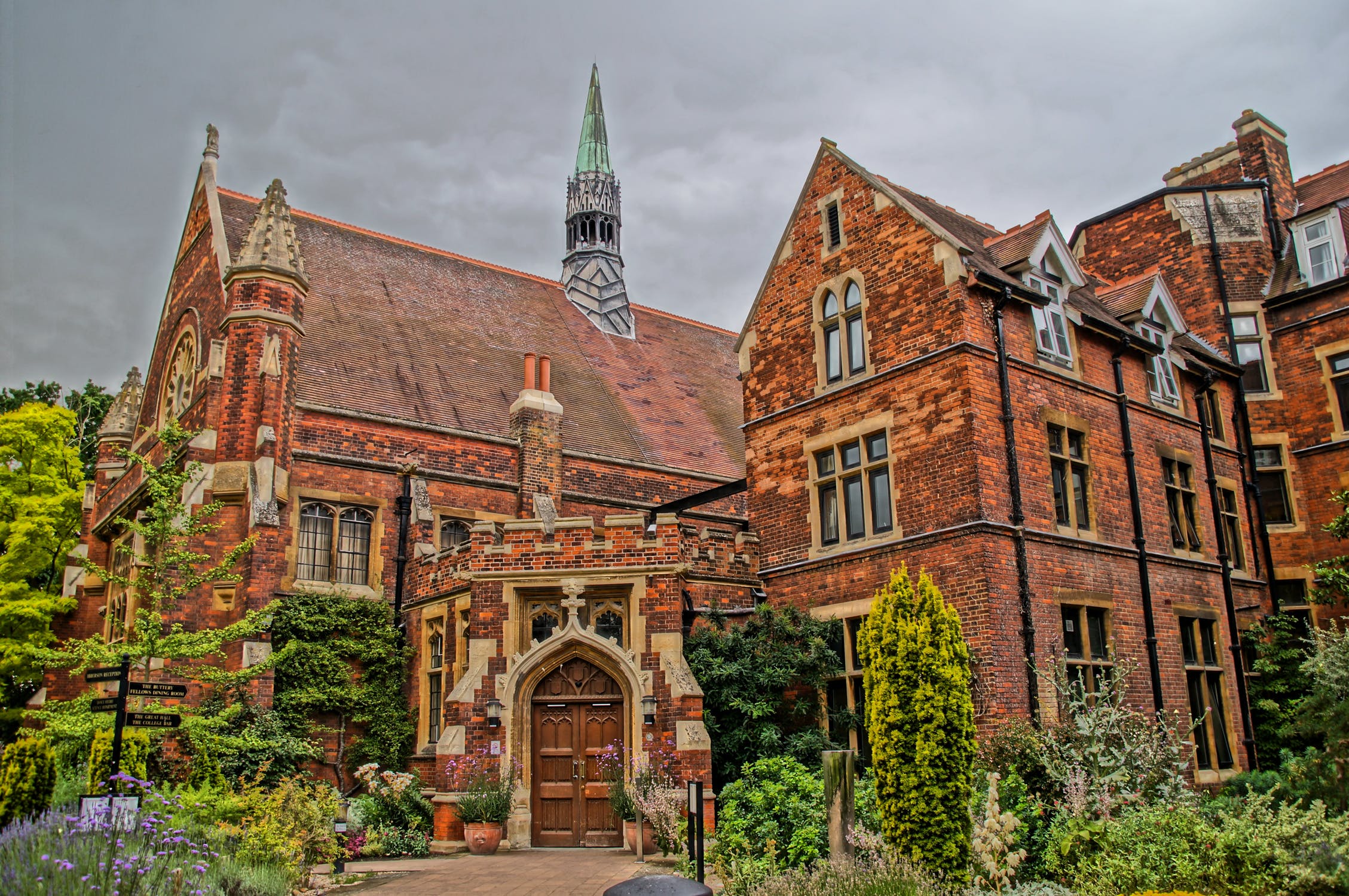 old red brick building with garden and cloudy sky