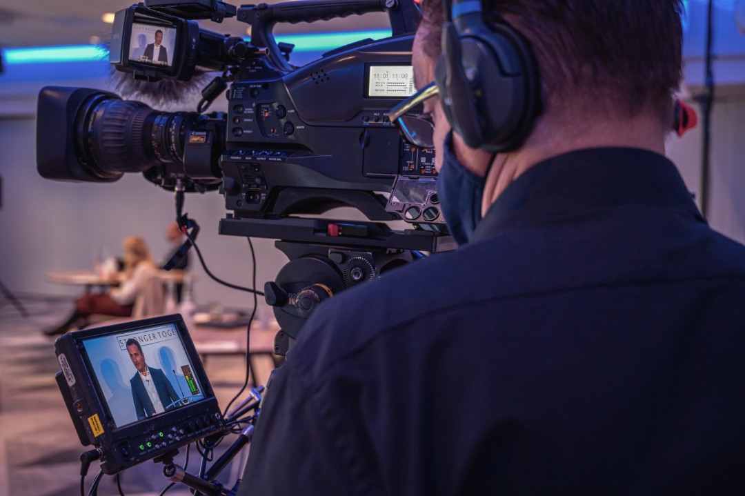 cameraman filming man giving a speech indoors