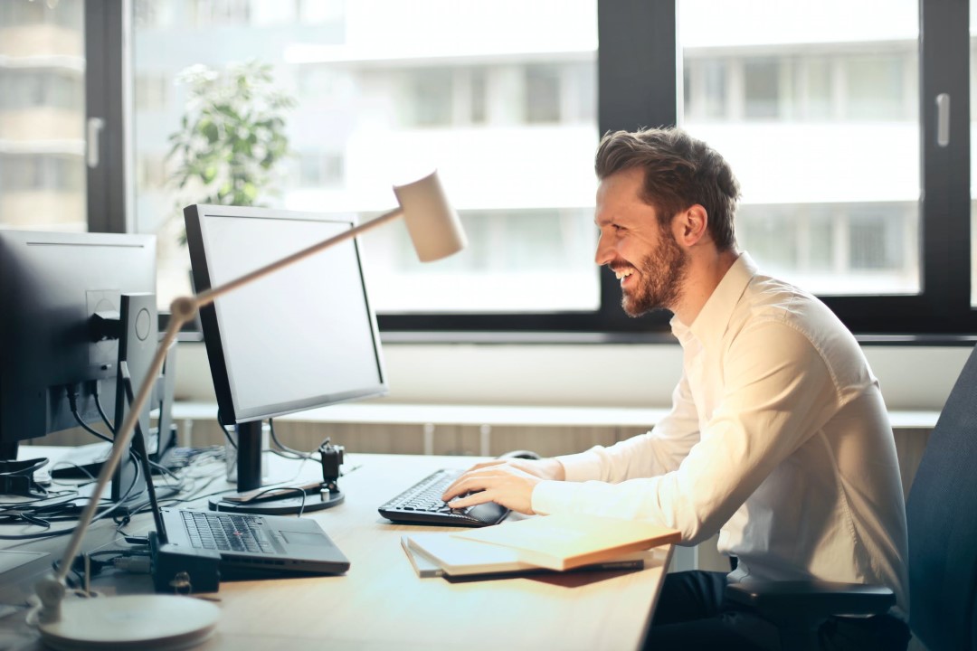 man smiling typing on keyboard at office desk