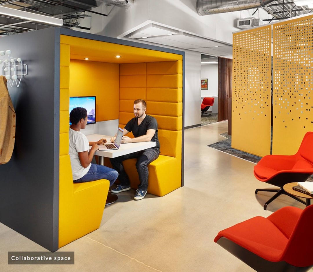 two people working with laptops in yellow booth