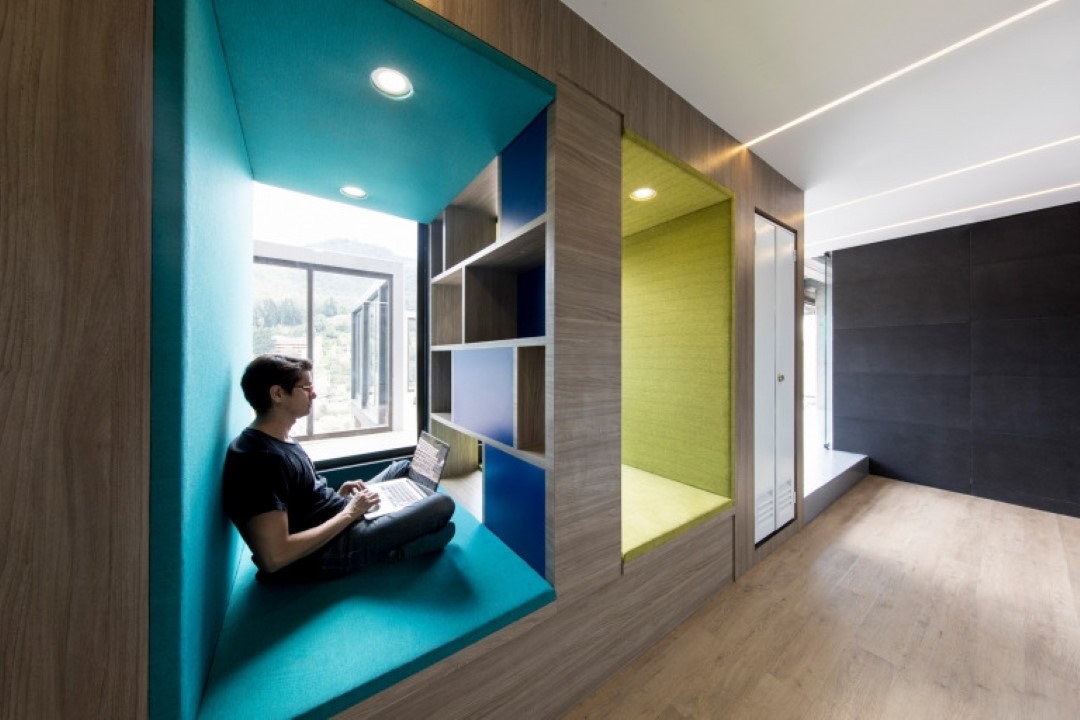 person working on laptop in modern cushioned nook