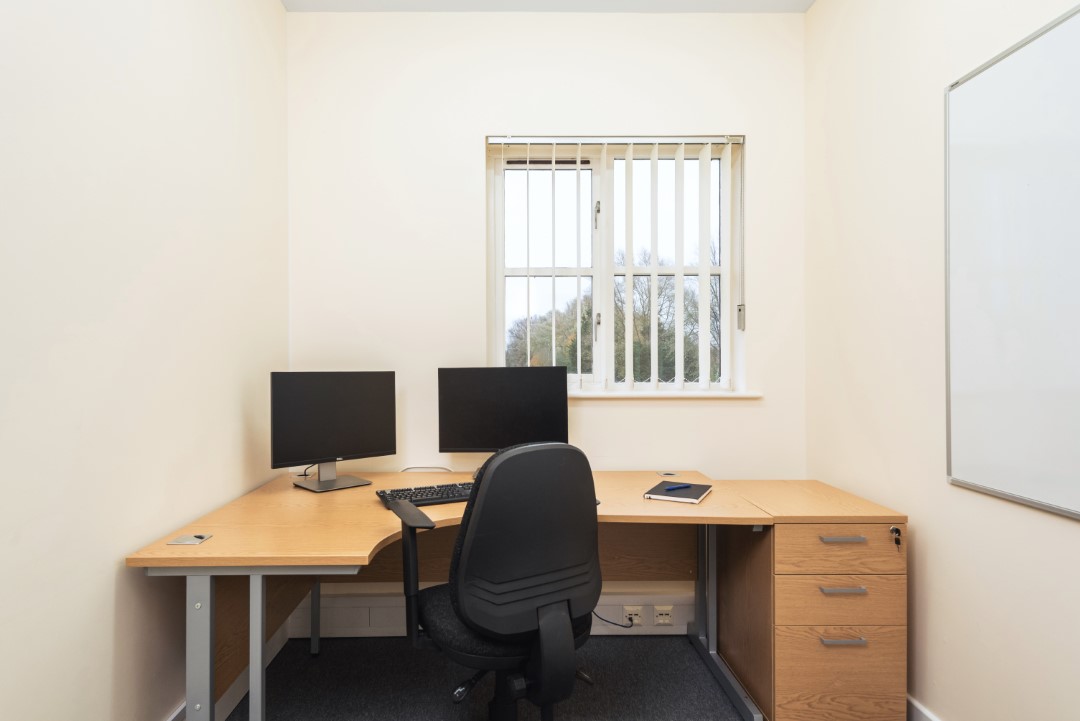 empty office desk with two monitors and chair