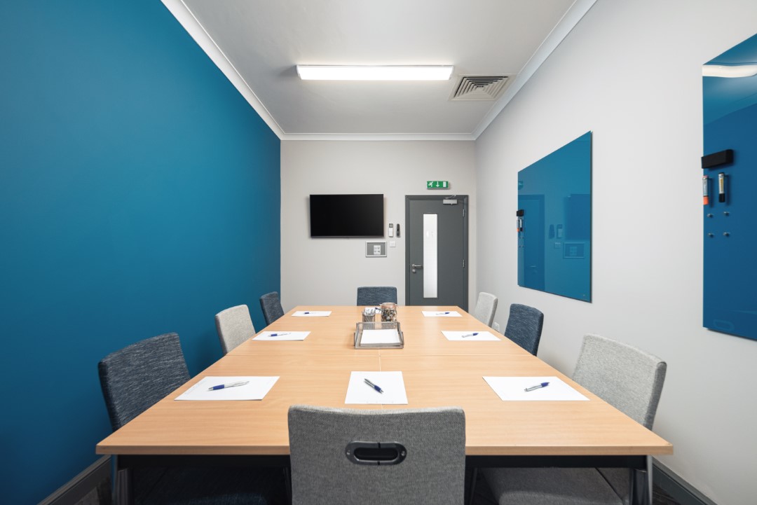 conference room with blue walls pens and paper on table