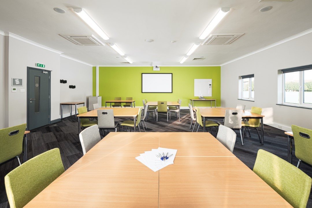empty classroom with wooden tables green chairs and whiteboard