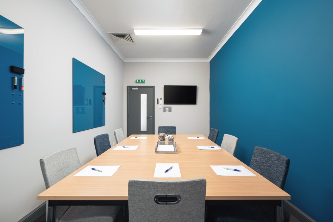 empty meeting room with table chairs and blue boards