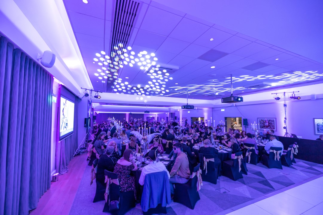 large formal dinner party with purple lighting
