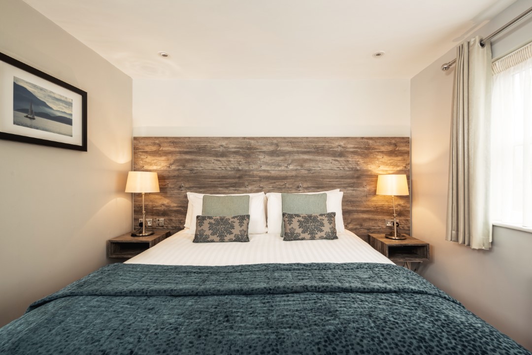 double bed with bedside lamps and wooden headboard