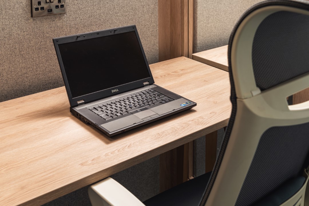 old laptop on wooden desk with office chair