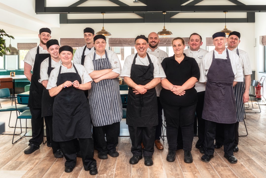 group of eleven chefs and restaurant staff standing smiling