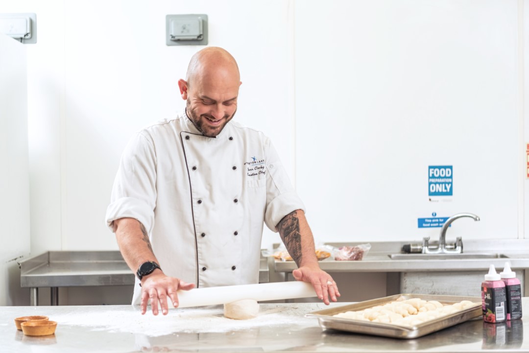 chef rolling dough on floured stainless steel counter