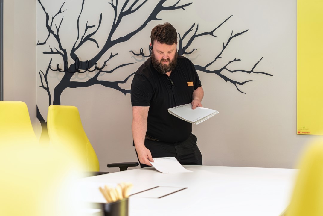 man in black shirt arranging papers at white table