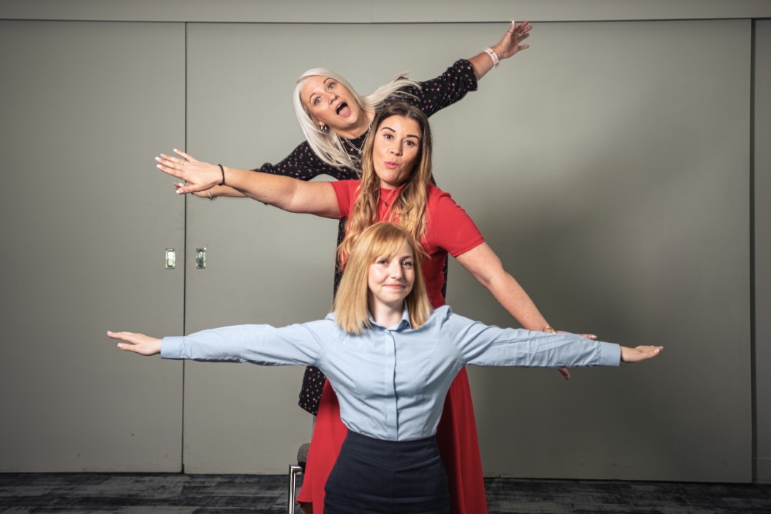 three women standing in line with arms stretched out