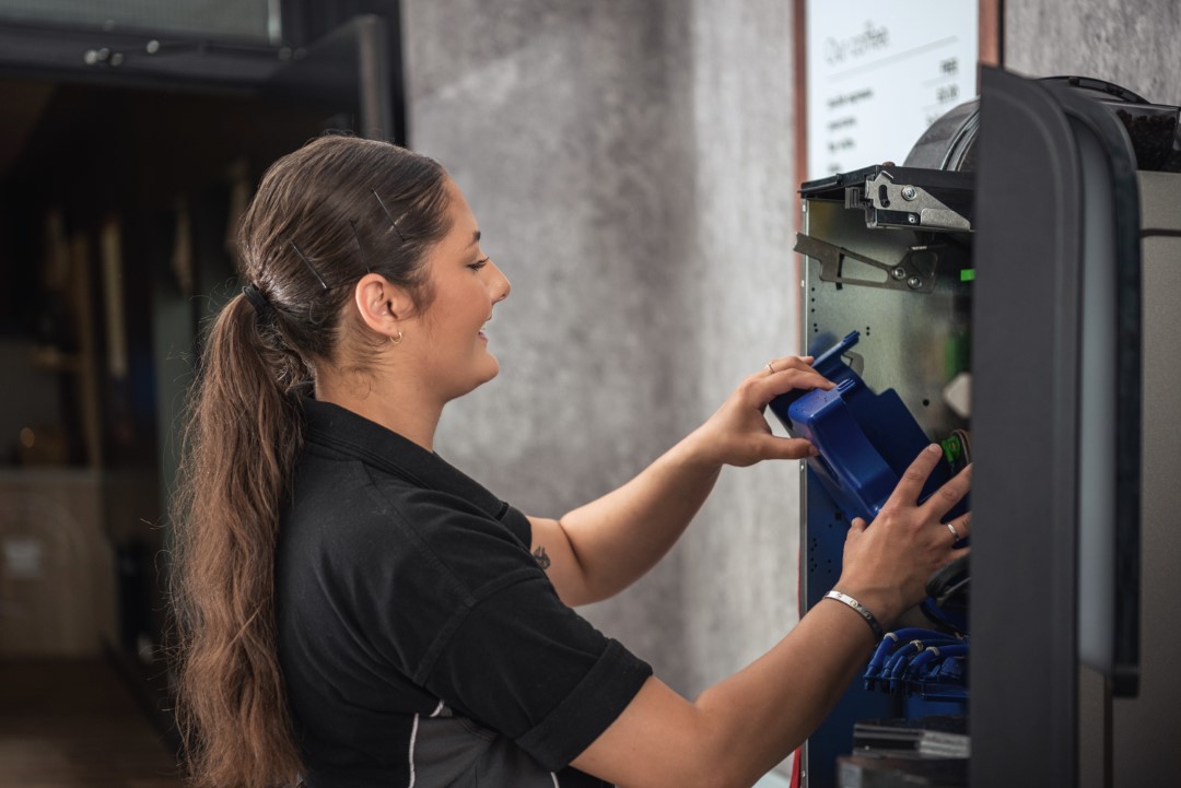 woman repairing or fixing vending machine indoors