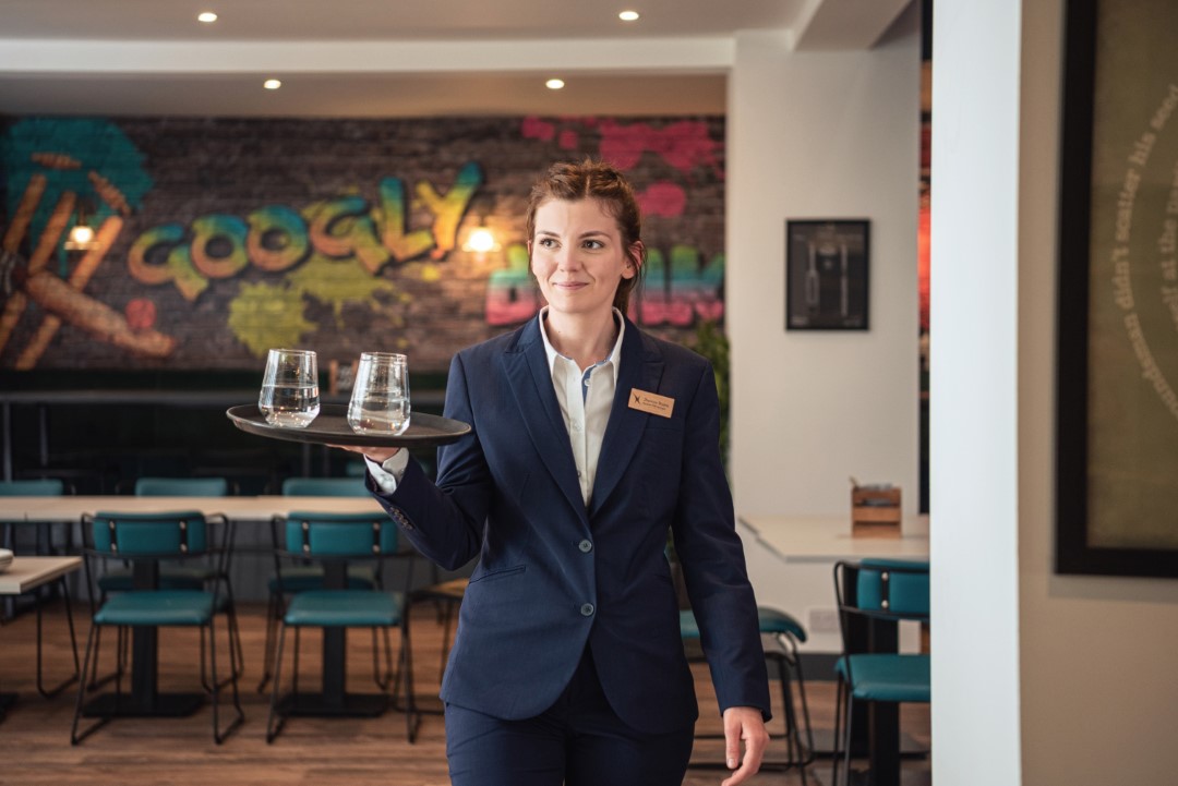 waitress carrying tray with glasses in casual restaurant