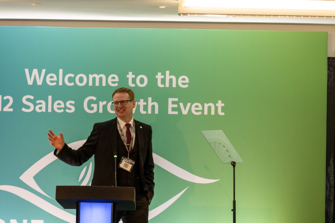 man speaking at sales growth event podium