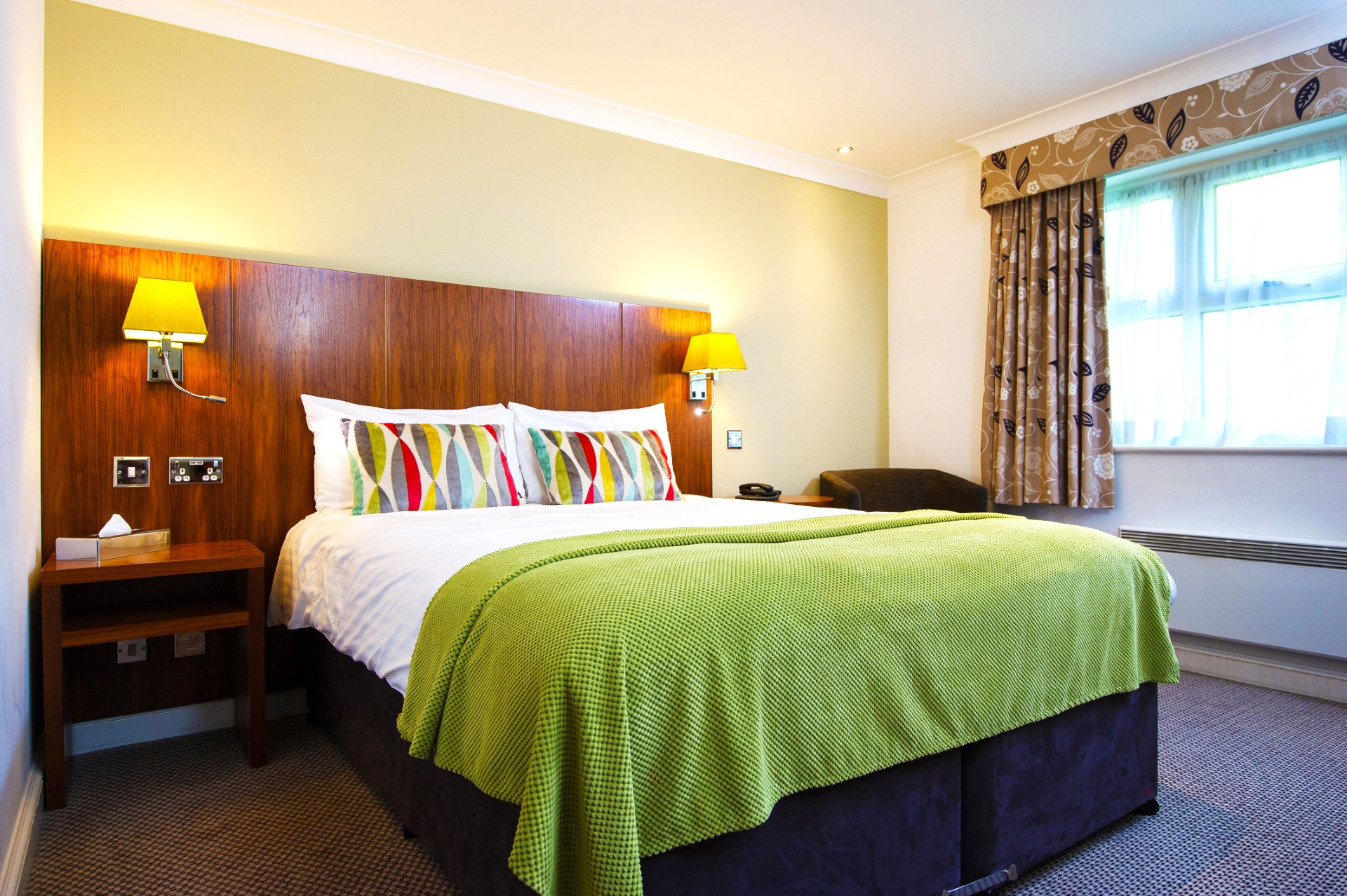 double bed with green blanket bedside tables and lamps