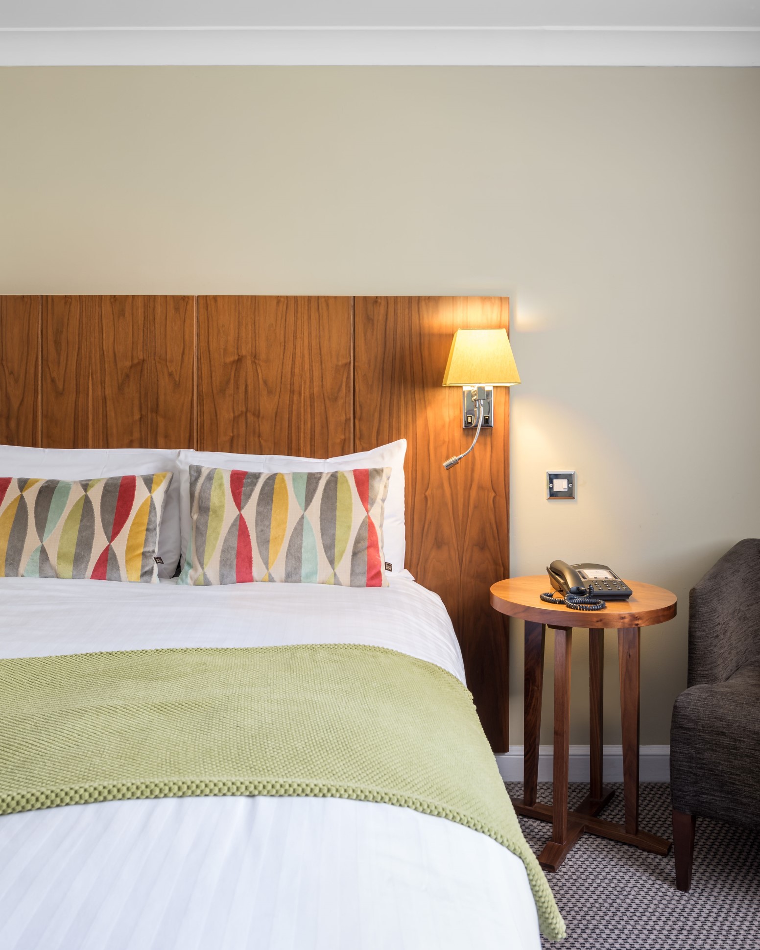 double bed with patterned cushions wooden headboard bedside table and