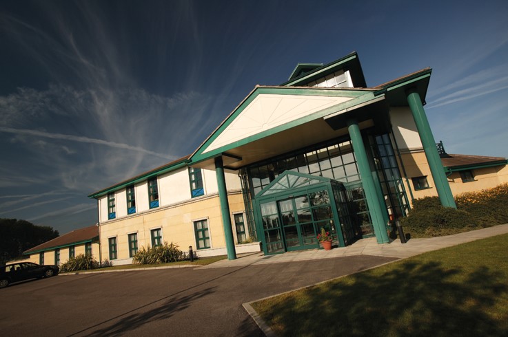 modern two storey building with green pillars and glass entrance
