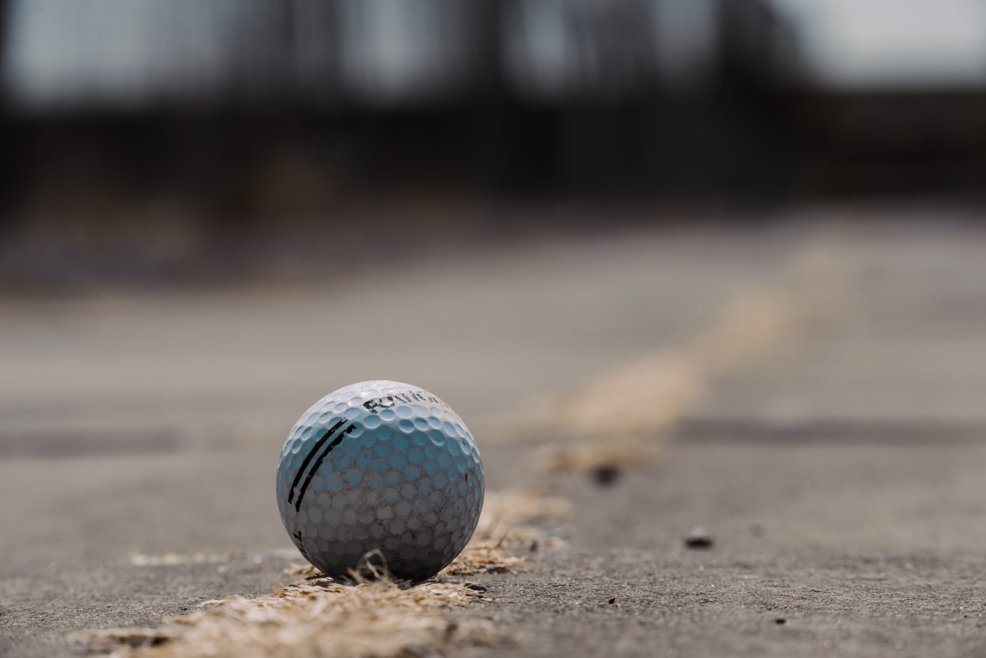 white golf ball on cracked concrete ground with yellow line