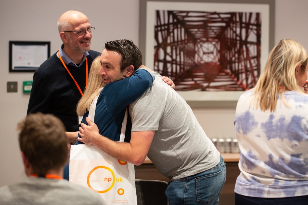 people hugging at indoor event with badges