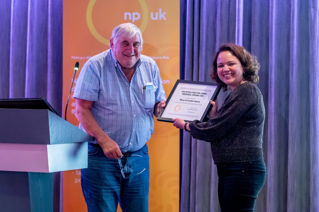 two people smiling holding an award certificate