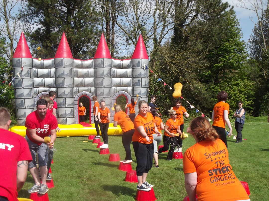 people playing outdoor game with sponges and inflatable castle