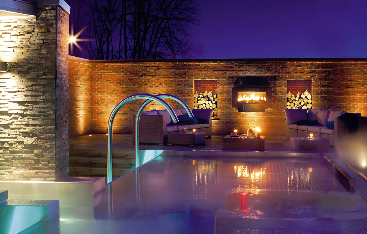 outdoor pool area with fire pit and seating at night