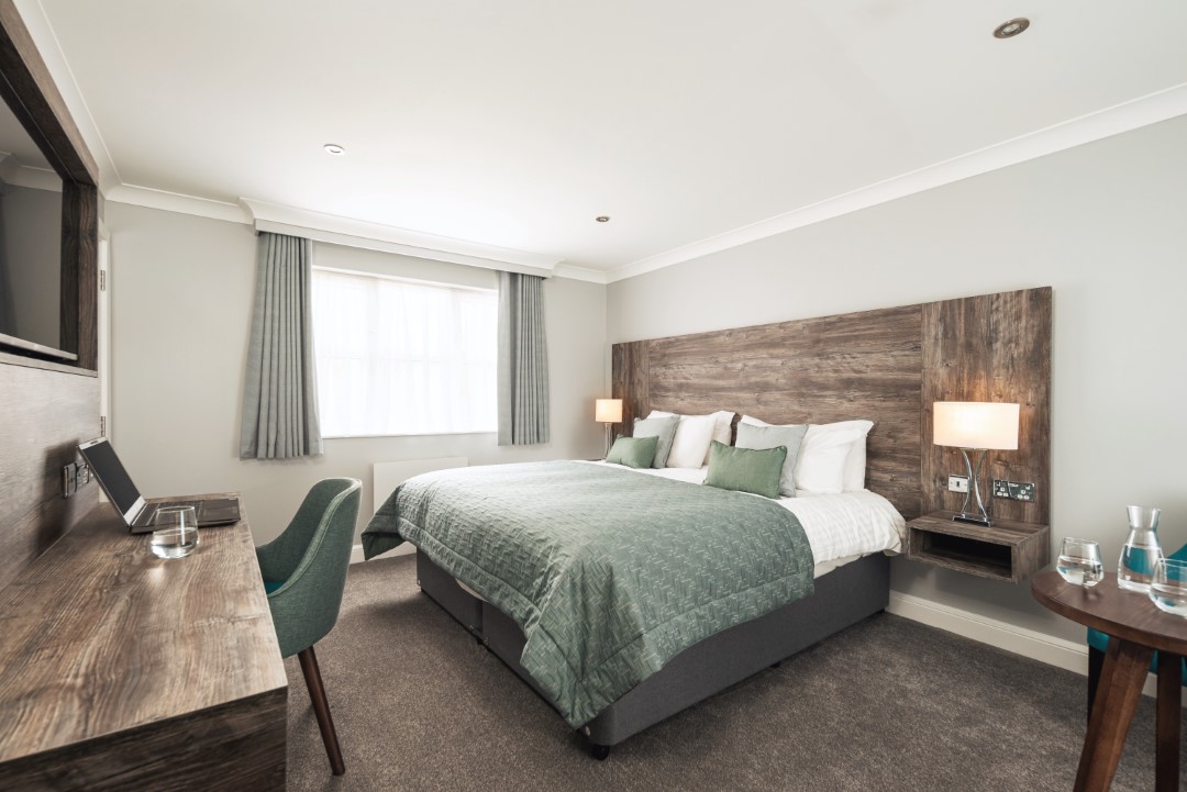 modern hotel room with double bed and desk setup