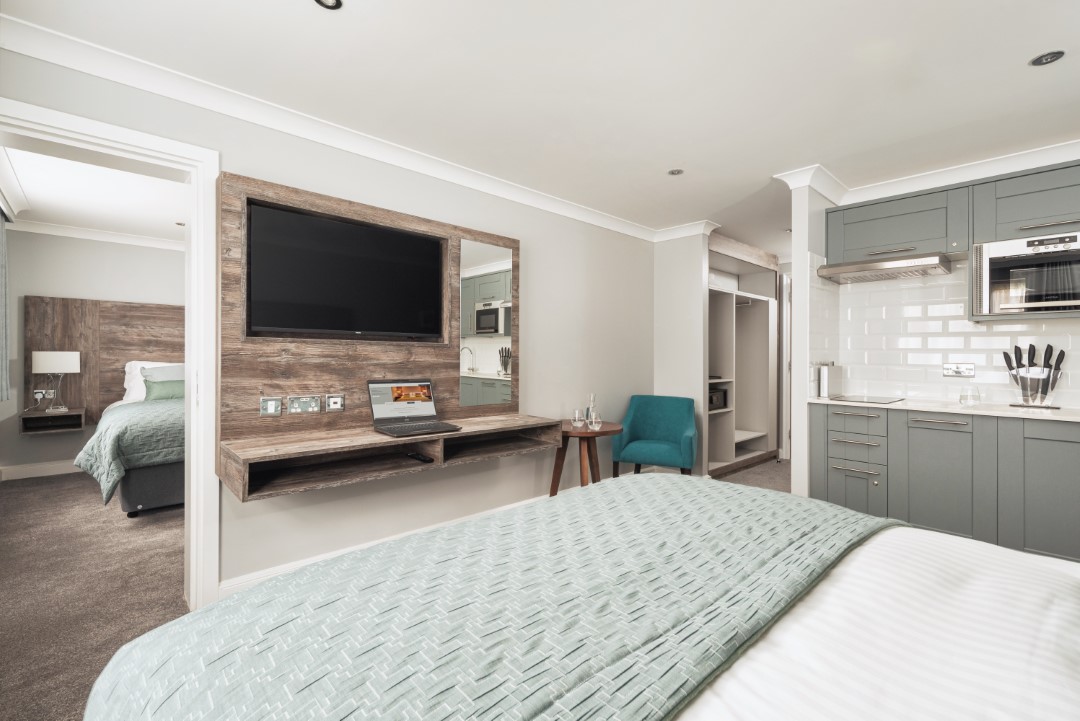 modern hotel room with kitchenette and bedroom visible