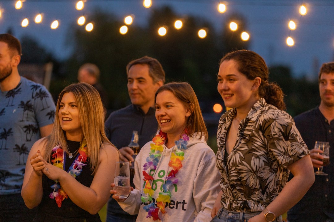 group of people smiling at evening party with string lights