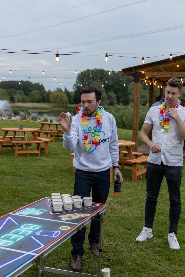 two men playing beer pong outside with floral leis