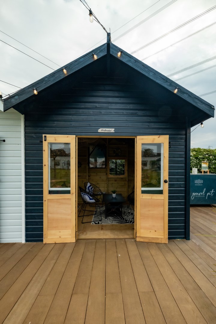 black wooden shed with open natural wood doors and chairs