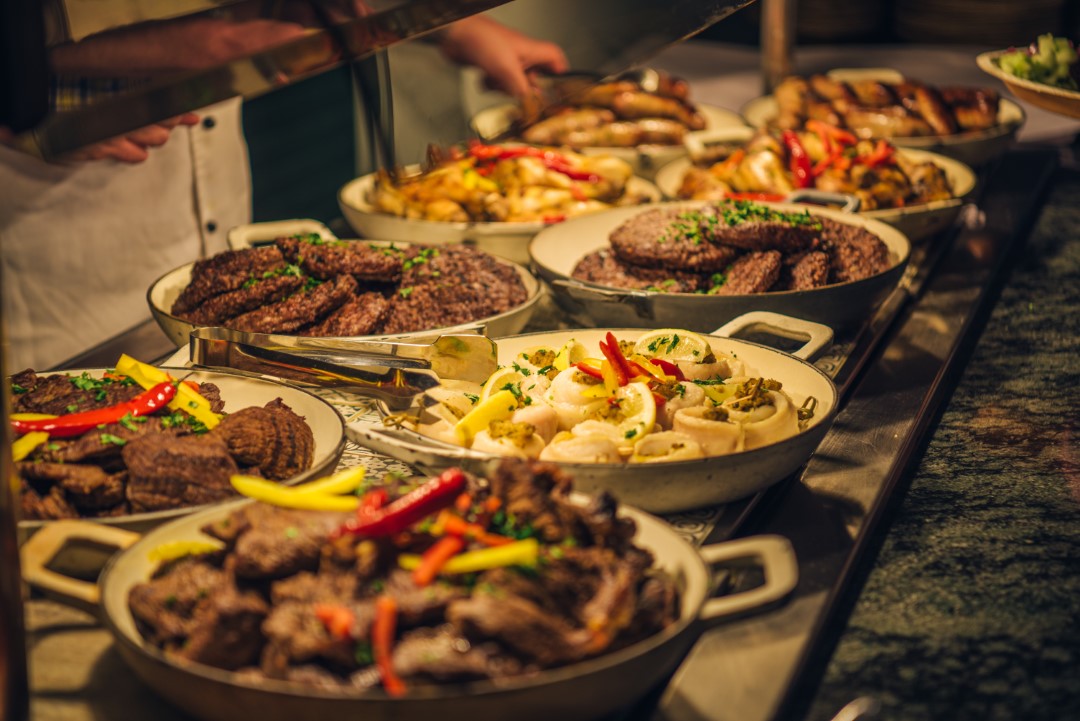 buffet dishes with meat and vegetables on display