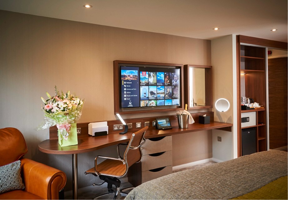 hotel room desk with chair tv and flower bouquet