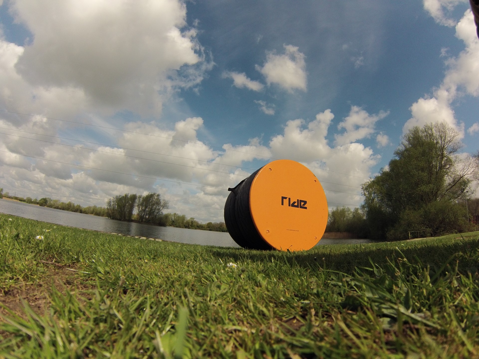 yellow round object on grass near lake under cloudy sky