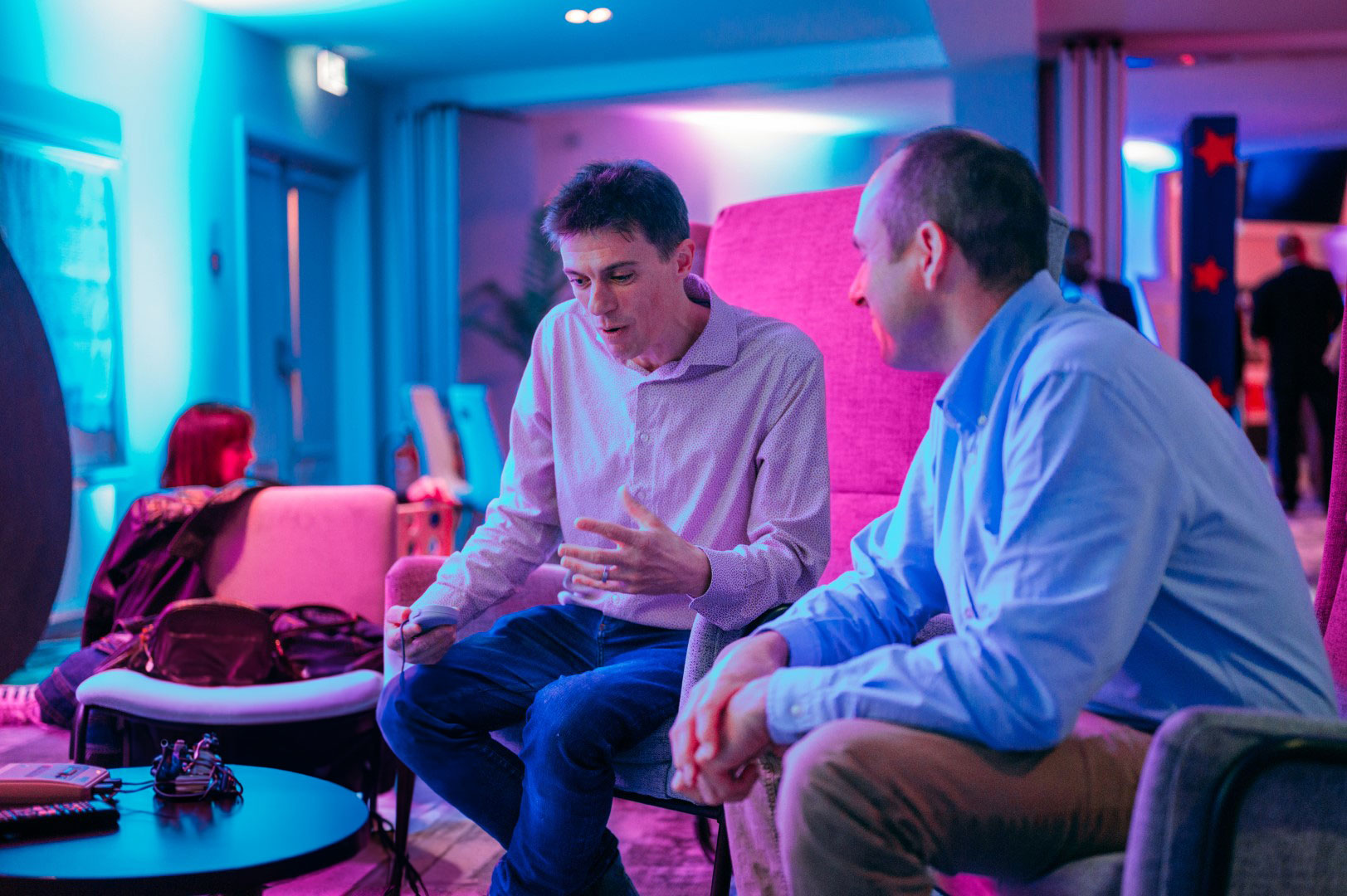 two men talking sitting in colourful lit room