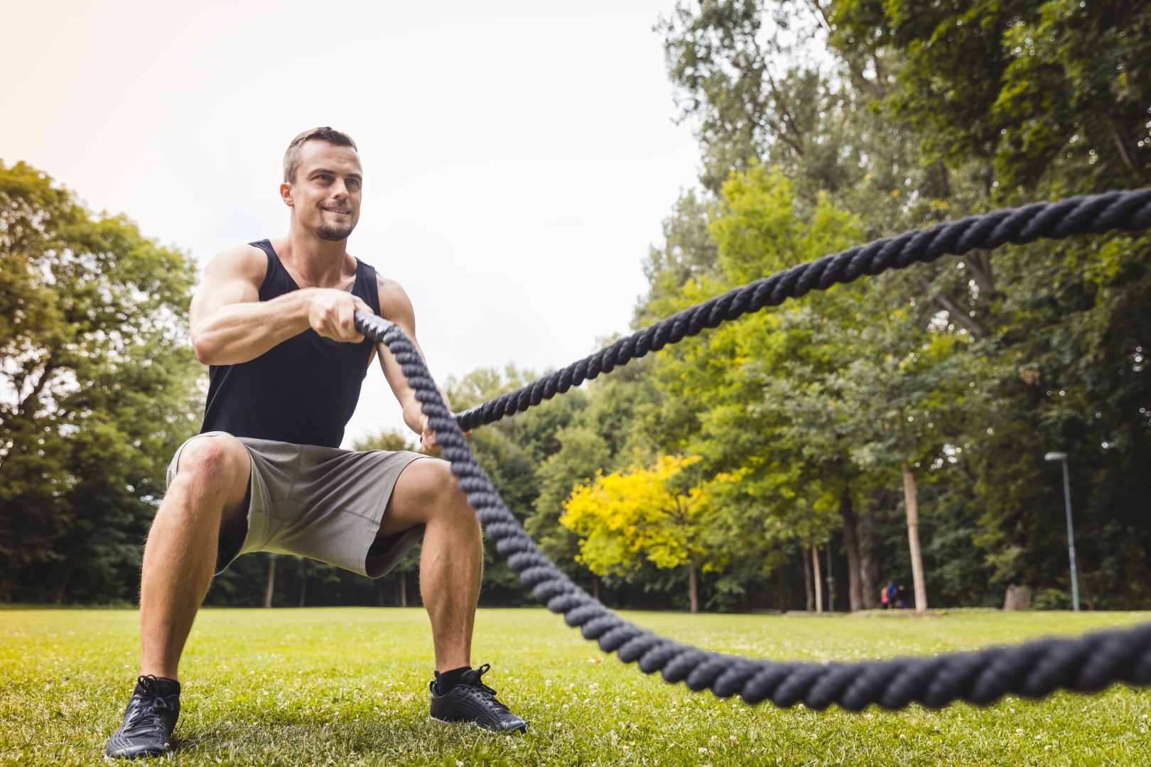 man exercising with battle ropes outdoors in park