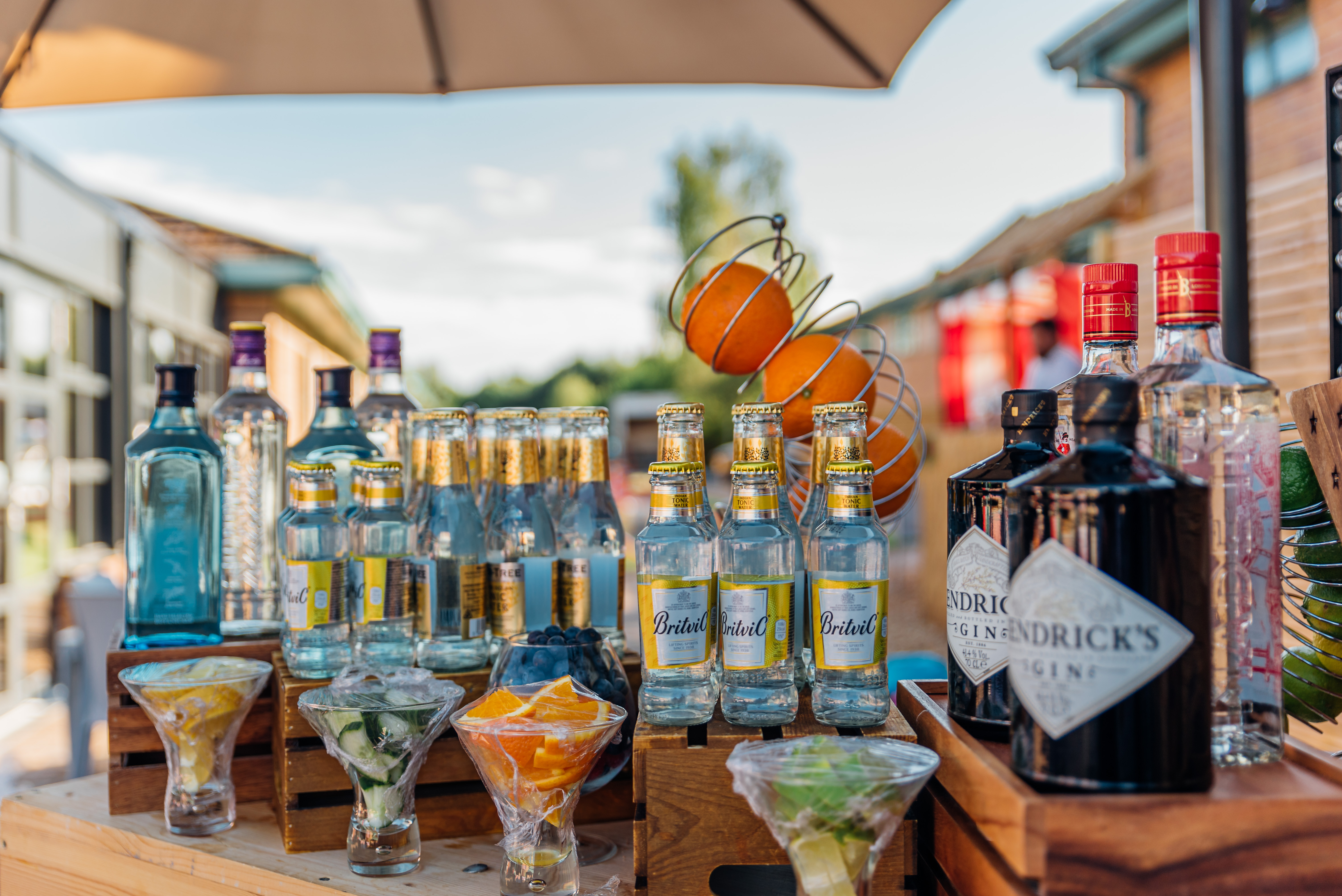 bottles of gin tonic mixers and fruits on wooden bar