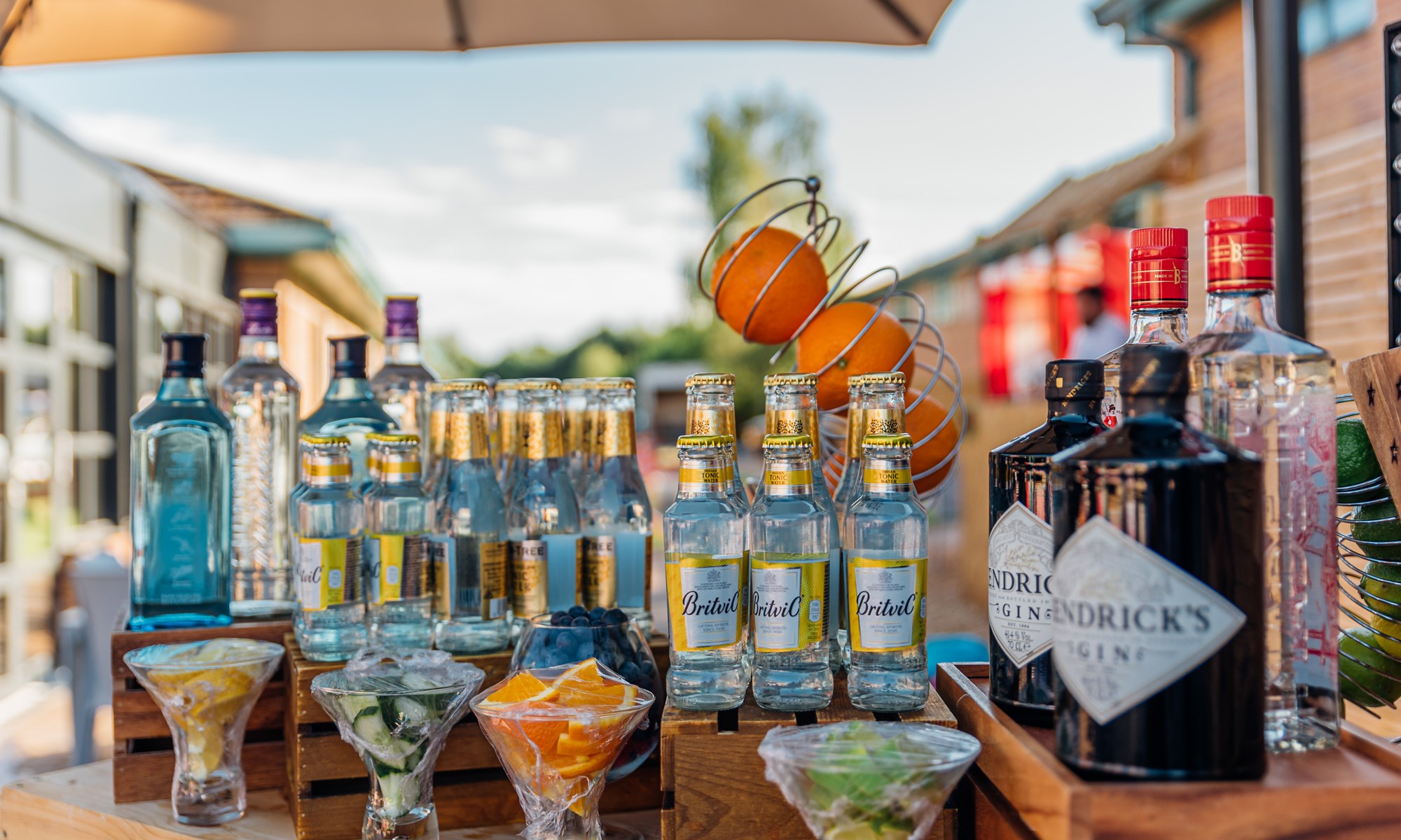 bottles of gin tonic mixers and fruits on wooden bar