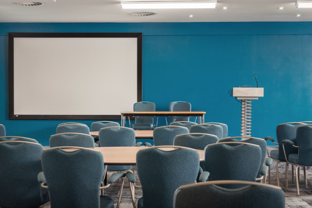 empty conference room with chairs tables podium and screen