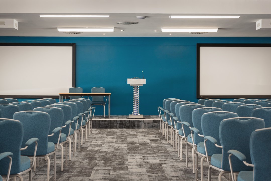 empty conference room with rows of blue chairs (1)