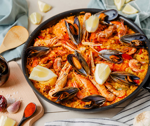 seafood paella with prawns mussels and lemon wedges