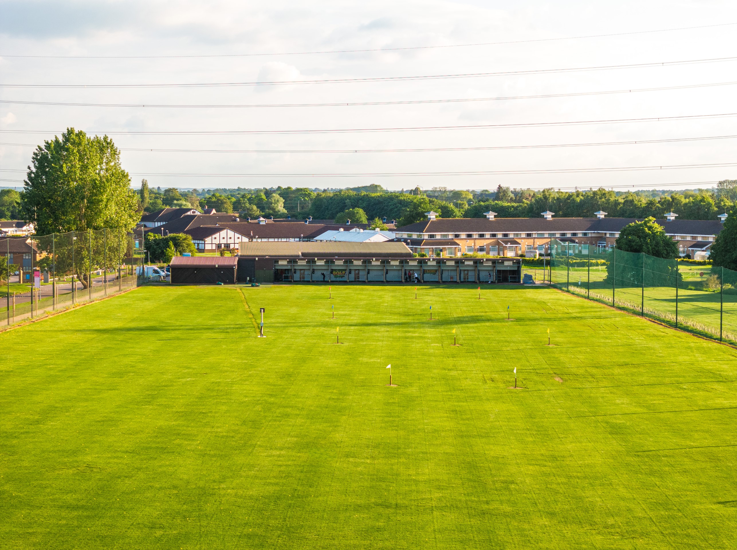 wide view of golf driving range with houses behind