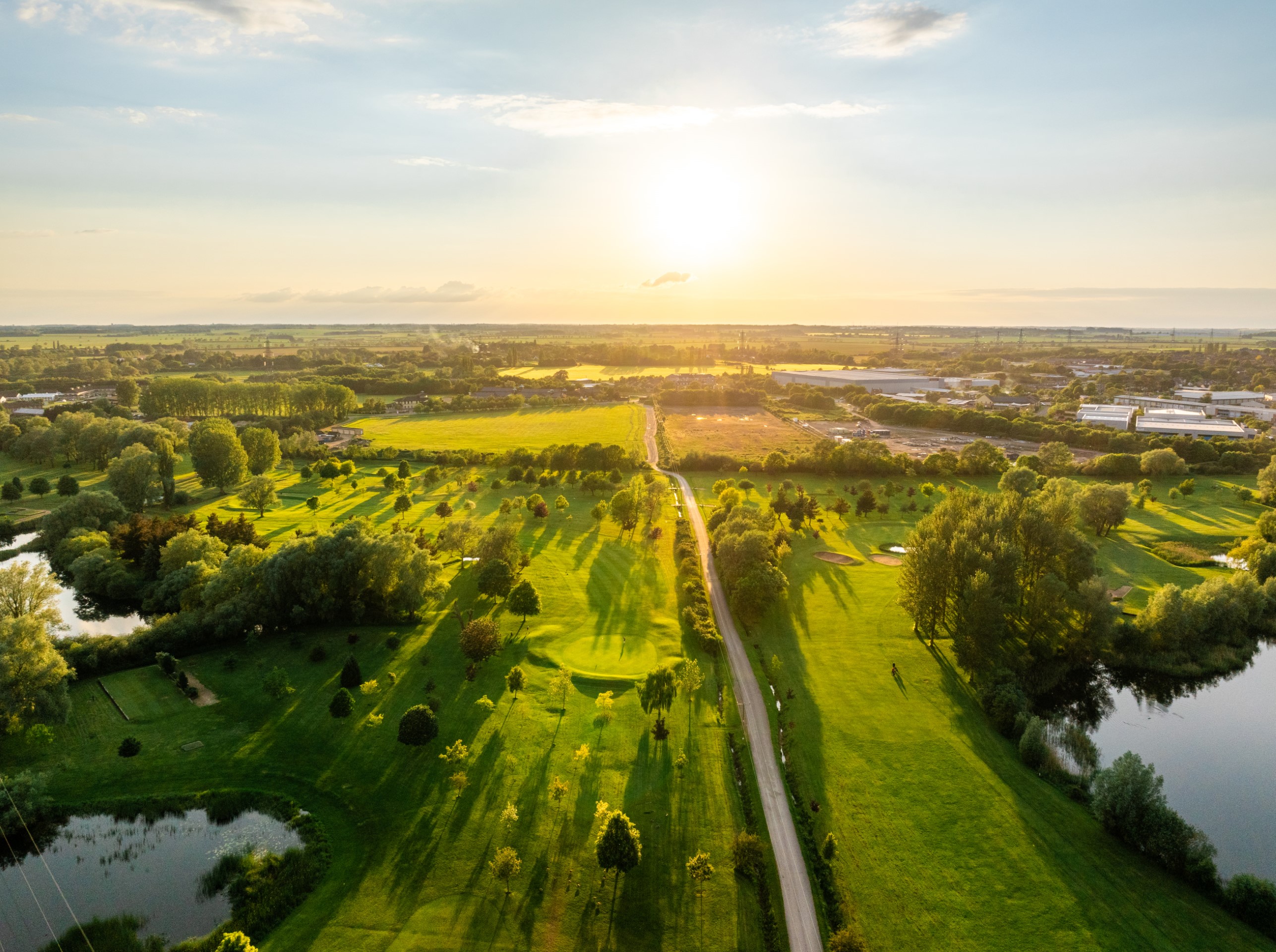 aerial view of green fields and trees at sunset