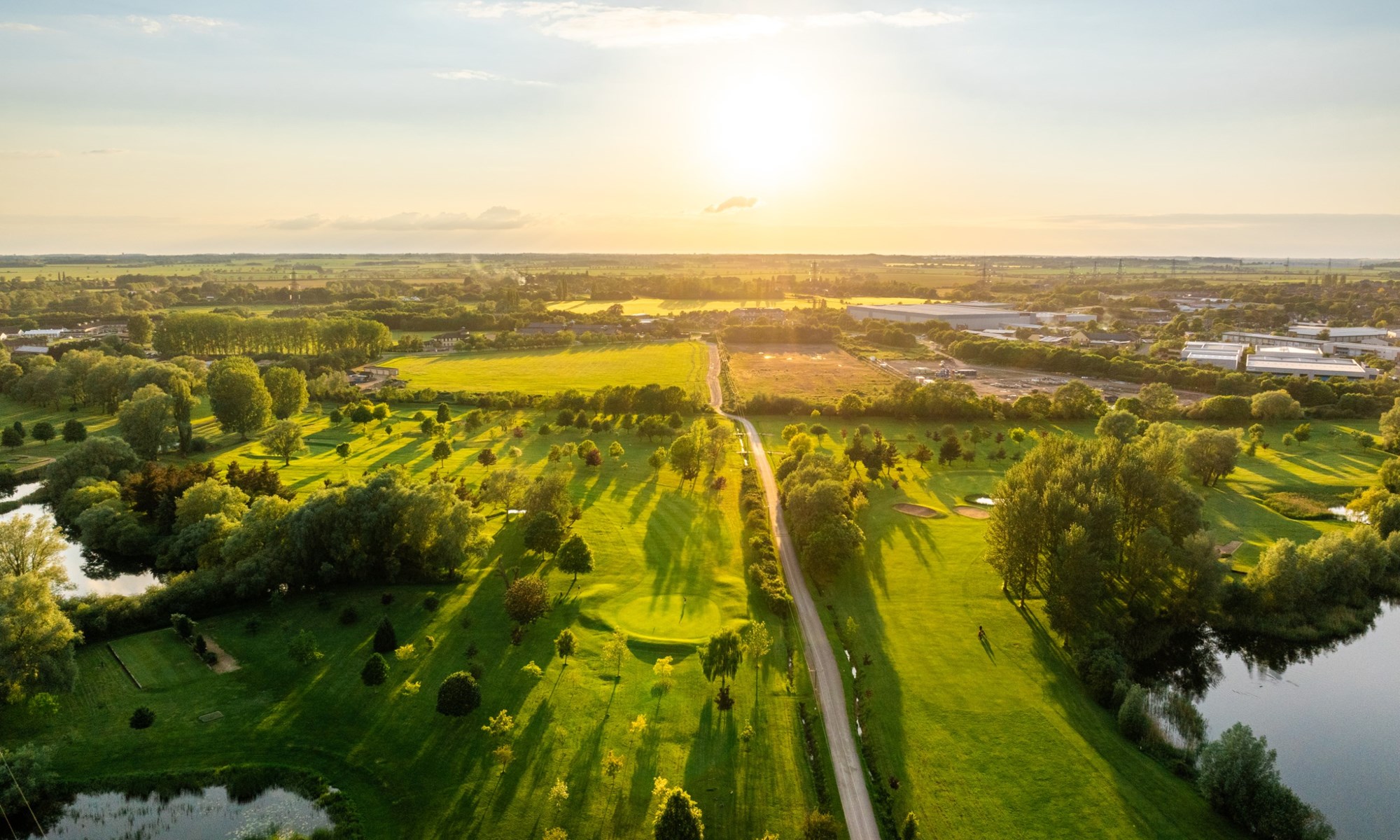 aerial view of green fields and trees at sunset